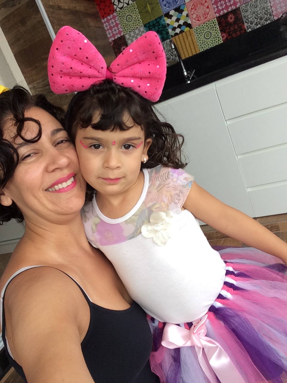 Foto: mulher branca cabelos pretos ondulados e curtos e com em torno de 40 anos e uma menina de em torno de 4 anos branca de cabelos castanhos lisos abraçadas e sorrindo
