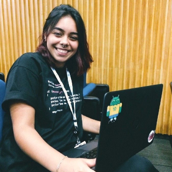 Foto de uma mulher branca cabelos curtos e castanhos, com em torno de 20 anos com um notebook